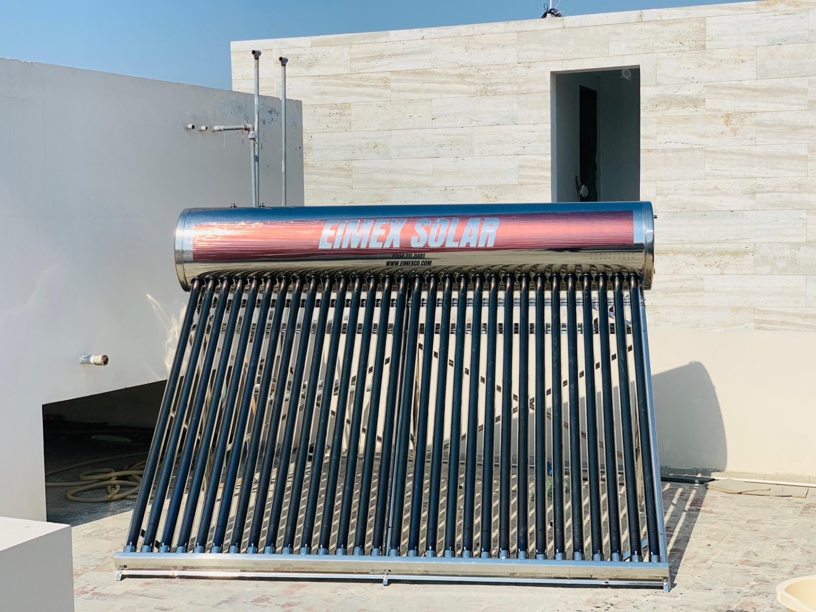 EIMEX solar geyser installed against a stone wall on a residential rooftop
